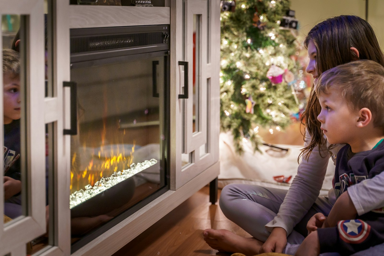 woman in gray long sleeve shirt sitting on floor beside fireplace